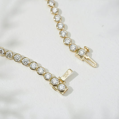 Pulsera de tenis de oro amarillo de 18 quilates con engaste de bisel y cadena de tenis con diamantes redondos DEF VS cultivados en laboratorio.